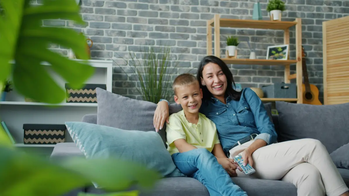 Mother and son smiling on the sofa while watching TV together