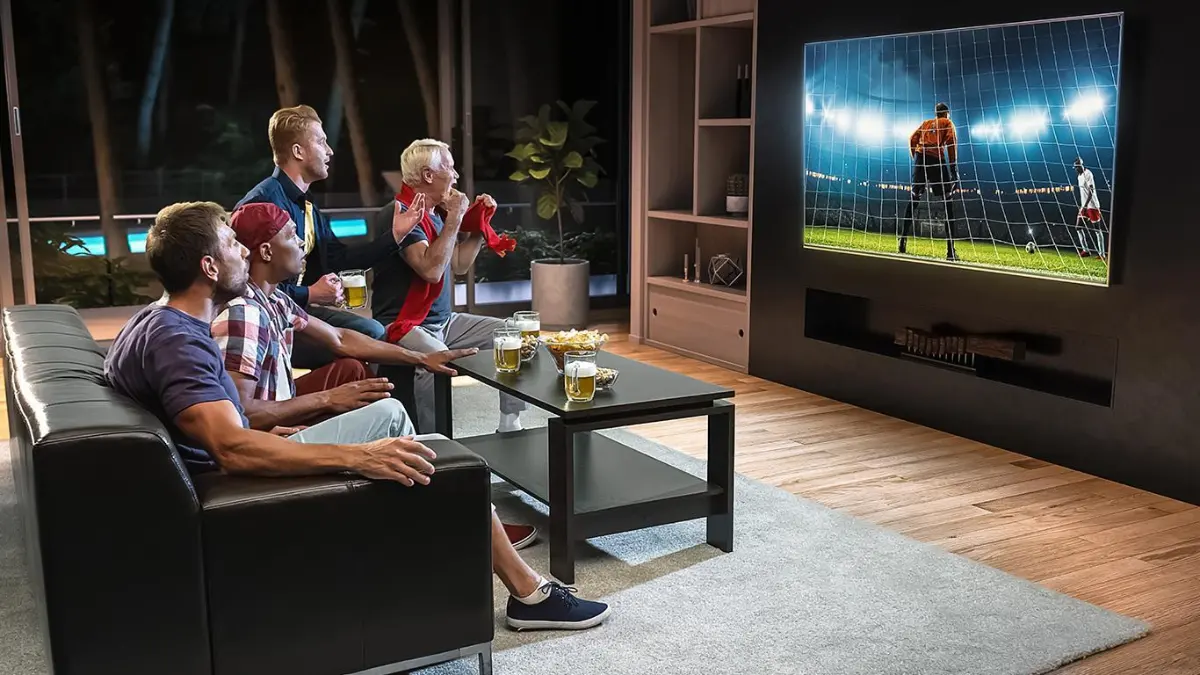 Friends cheering while watching a live football match on a big TV